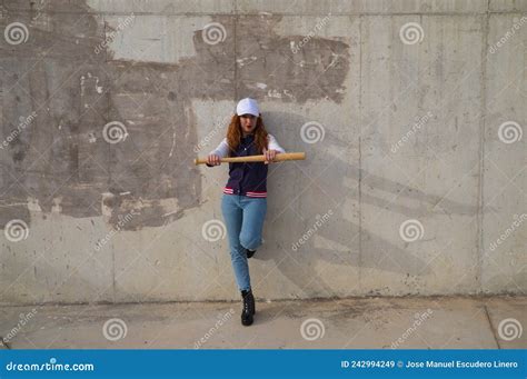 Young And Beautiful Redhead Woman Is Happy With Baseball Cap Jacket Baseball Bat And Jeans