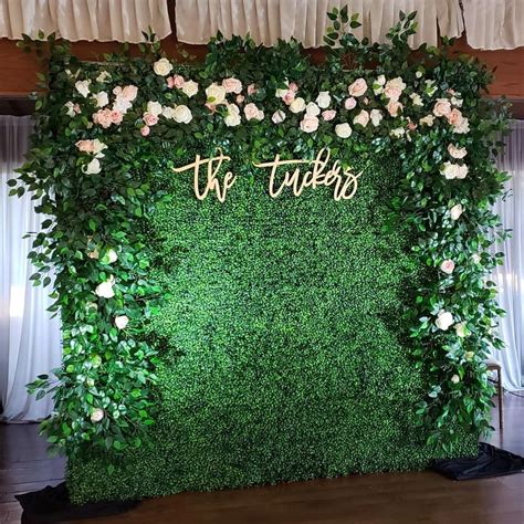 The Wedding Backdrop Is Covered With Greenery And Flowers