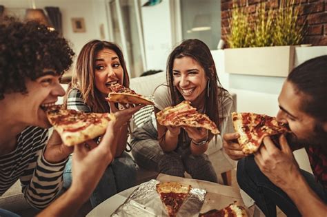 los amigos emocionados están en casa sentados en el sofá sus amigos traen pizza para comer