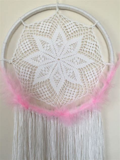 A White And Pink Dream Catcher Hanging On A Wall