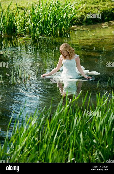 Woman Lady Walking Into Lake Water Up To Her Waist In Long Wedding Dress With Lily Pads And