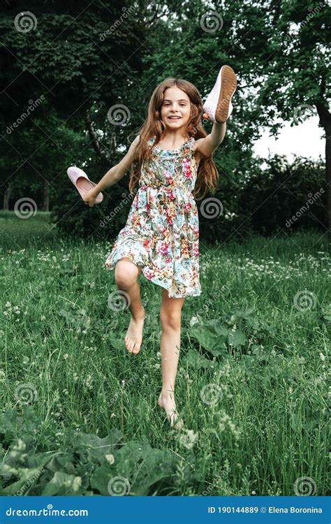 Teenage Girl With Long Hair In A Dress Smiles And Jumps Barefoot On The