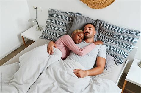 Diverse Young Couple Lying Sound Asleep In Each Others Arms In Their Bed In The Early Morning