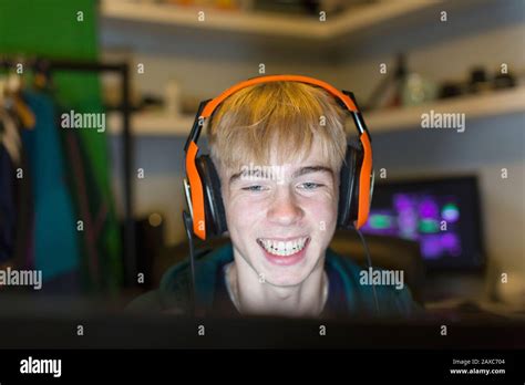 Happy Teenage Boy With Headset Playing Video Game At Computer Stock