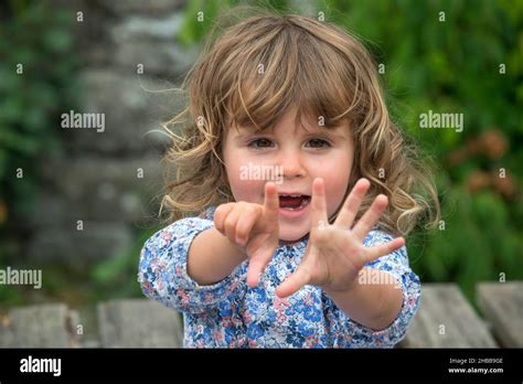 Two Year Old Girl Blonde Outdoors Counting On Her Fingers Stock