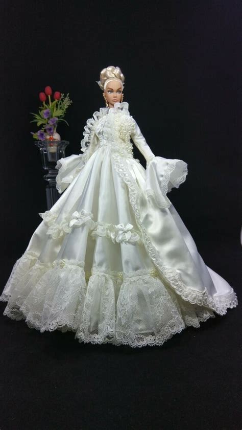 The Doll Is Wearing A White Dress With Ruffles