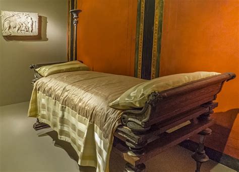 An Old Fashioned Wooden Bed In A Room With Orange Walls