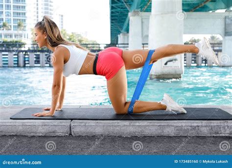 fitness woman doing exercise for glutes with resistance band outdoors athletic girl workout