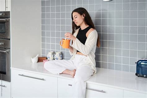 Beautiful Woman Having Coffee Sitting On Counter By Stocksy