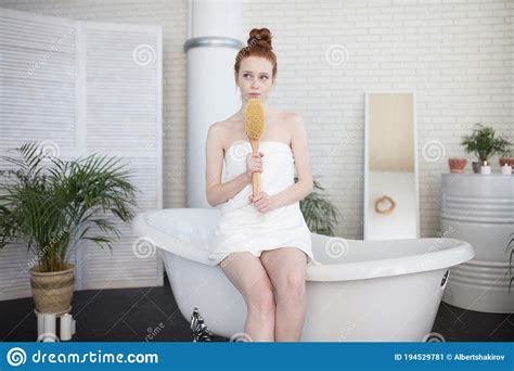 red haired woman massaging her legs with body brush in bathroom stock image image of bath