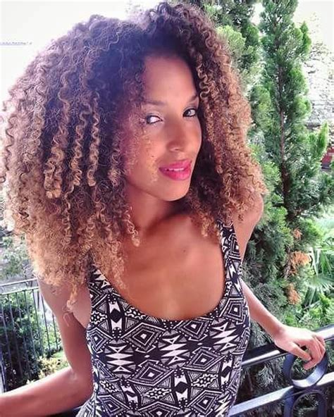 A Woman With Curly Hair Standing On A Balcony
