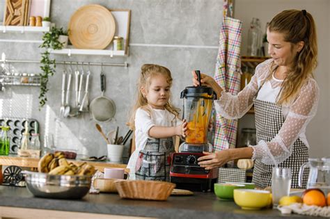 Daughter Assisting Her Mother In Preparing A Batter For A Dessert Stock