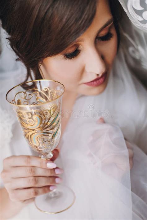 Beautiful Stylish Brunette Bride In Silk Robe And Veil Cheering With Glass Of Champagne In The