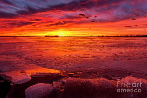 Colorful Sunrise Or Sunset On A Frozen Lake With Rocks In The Fo