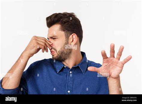 Man Holding His Nose Against A Bad Smell Isolated Over Grey Background