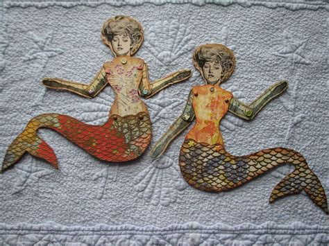 Two Paper Mermaids Sitting On Top Of Each Other