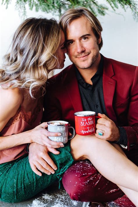 A Man And Woman Sitting Next To Each Other Holding Coffee Mugs