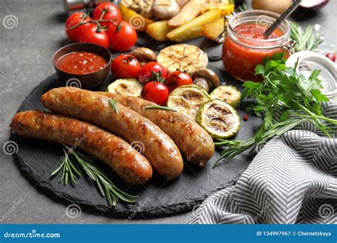 Slate Plate With Delicious Sausages And Vegetables Served For Barbecue