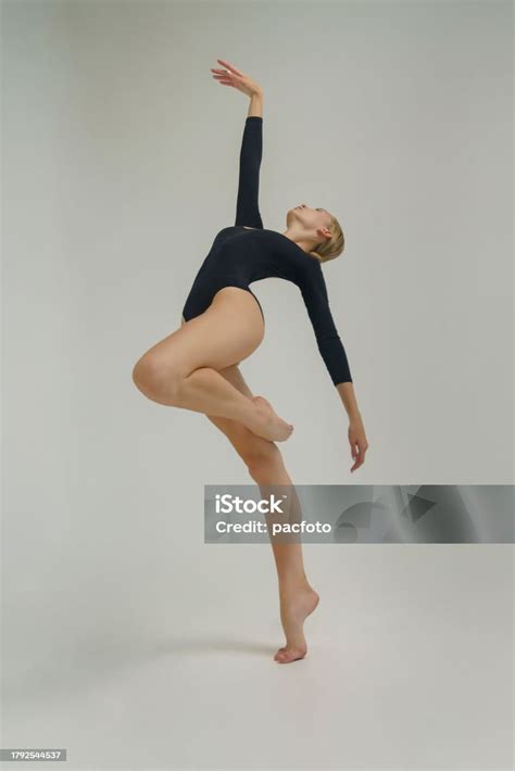 Young Ballerina In A Black Bodysuit Shows Ballet Steps In Motion