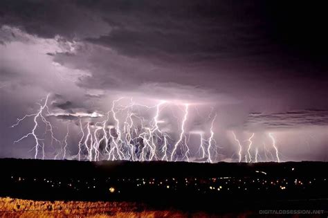 Several Lightning Strikes In The Sky Over A City At Night With Dark