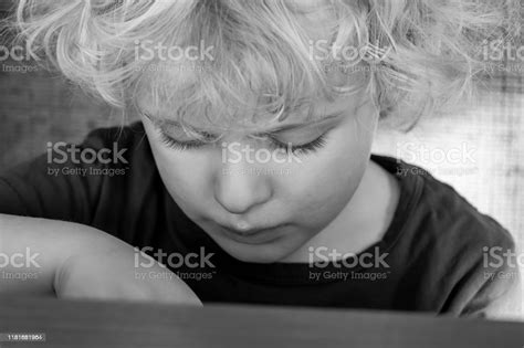 Black And White Photo Of Depressed Boy Looking Down Stock Photo