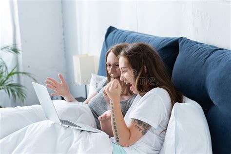 two smiling excited lesbians using laptop in bed in morning stock image image of girls love