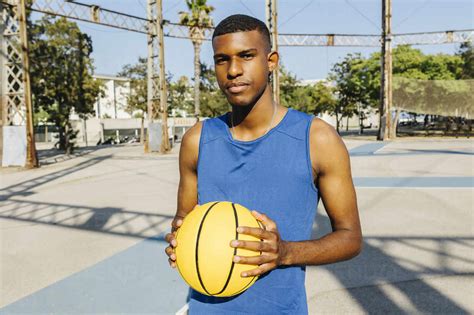 Young Man Holding Basketball In Sports Court Stock Photo