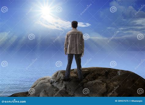 Young Man Standing On Rock Mountain And Looking To The Sun Royalty Free