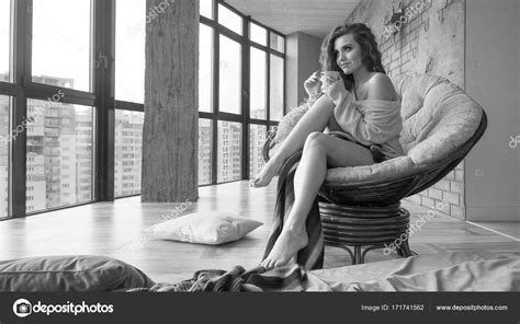 Sexy Woman Drinks Coffee While Sits In Armchair Early Morning Wearing