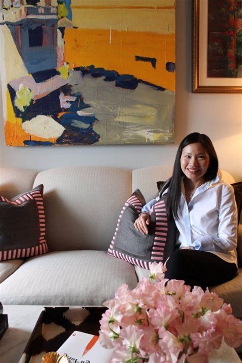 A Woman Sitting On Top Of A Couch Next To A Vase Filled With Pink Flowers