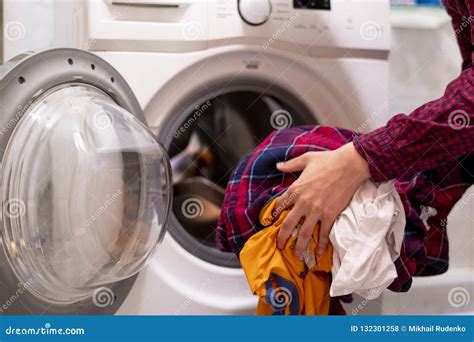 Close Up Hands Loading Dirty Clothes Into Washing Machine At Home