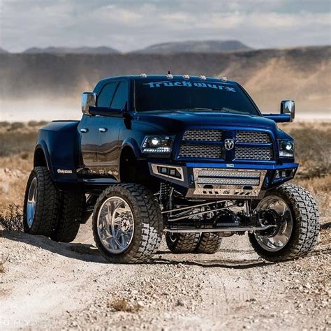 A Large Blue Truck Parked On Top Of A Dirt Road