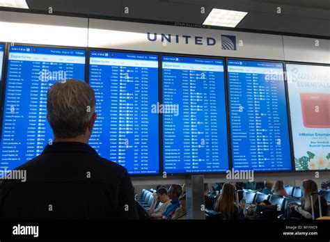 A Man Checking The Departure Board For United Airlines In Newark