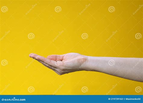 Female Hand Keeping Empty Cupped Palm Isolated On Yellow Background