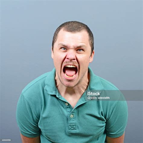 Portrait Of A Angry Man Screaming Against Gray Background Stock Photo