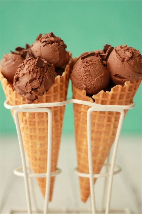 Three Ice Cream Cones With Chocolate Frosting In Them On A White Stand