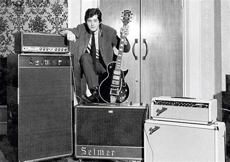 a man standing next to two guitars and amps