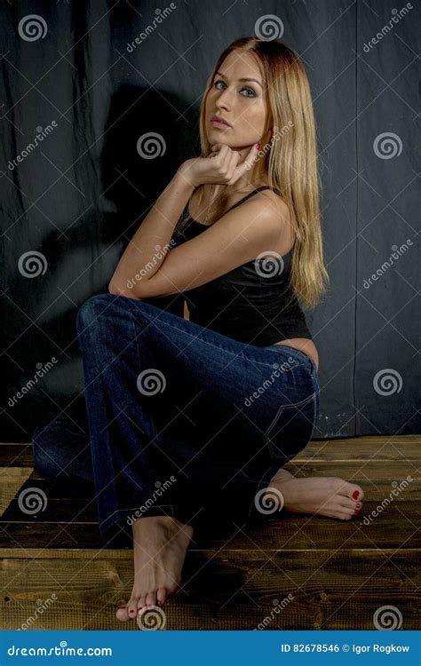 Young Slender Blonde Girl In Jeans And Shirt Posing Coquettishly Stock