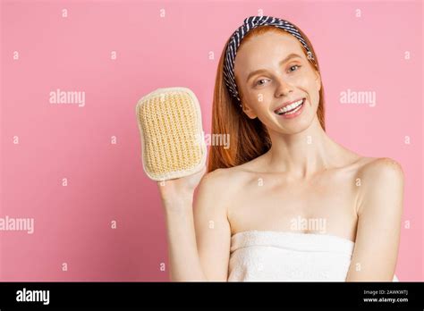 Joyful Caucasian Ginger Young Woman Standing Wrapped In White Towel On Pink Background Holding