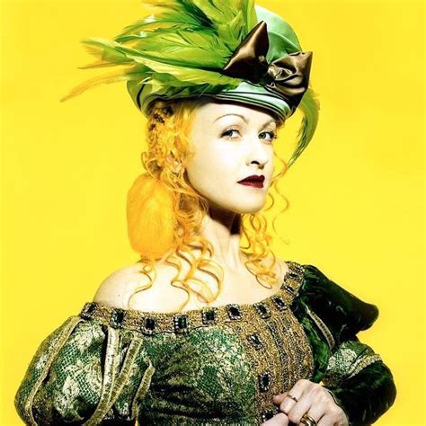 A Woman In A Green Dress And Hat With Feathers On Her Head Posing For