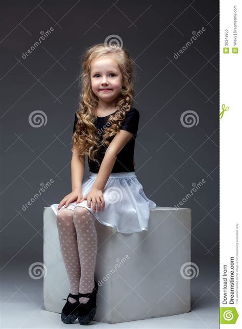 Smiling Cute Girl Posing Sitting On Cube In Studio Stock
