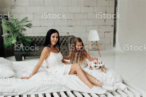 Beautiful Tanned Mom With Bare Legs And Her Daughter Are Sitting On The