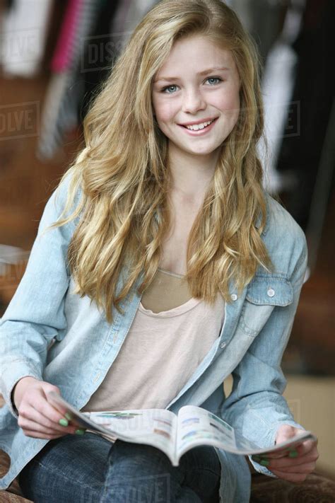 Teenage Girl With Long Blond Hair And Blue Eyes Reading A Magazine