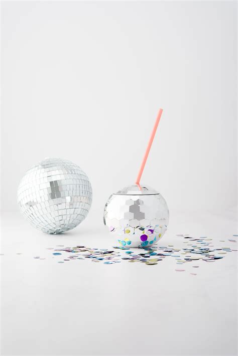 Two Disco Balls And A Straw In Front Of Them With Confetti On The Floor