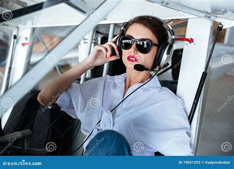 Attractive Woman Pilot In Sunglasses And Headset Sitting In Aircraft