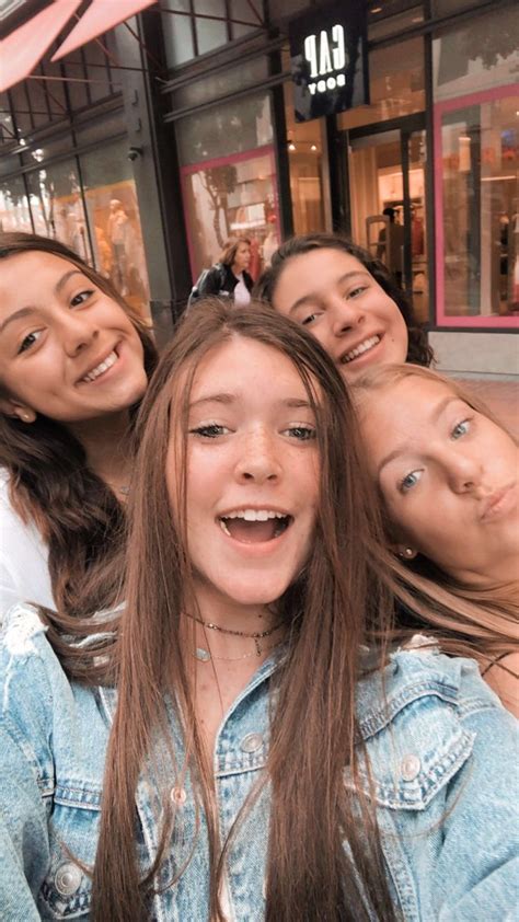 four girls posing for the camera in front of a store