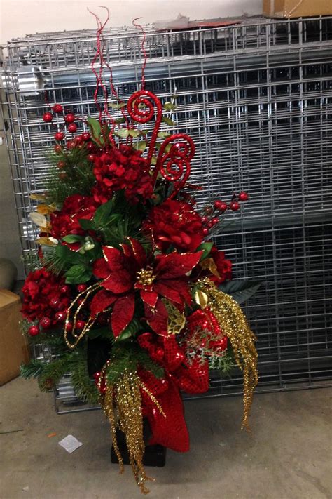A Christmas Arrangement With Red Flowers And Gold Sequins In Front Of A