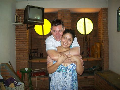 a man and woman hug each other in front of a television set with three round windows behind them
