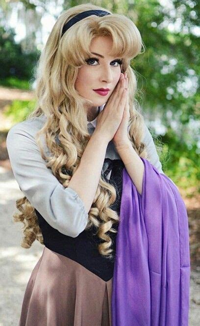 A Woman With Long Blonde Hair Wearing A Purple Scarf And Black Dress Posing For The Camera