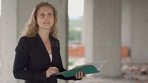 Female Architect Studying Drafts While Visiting Large Construction Site